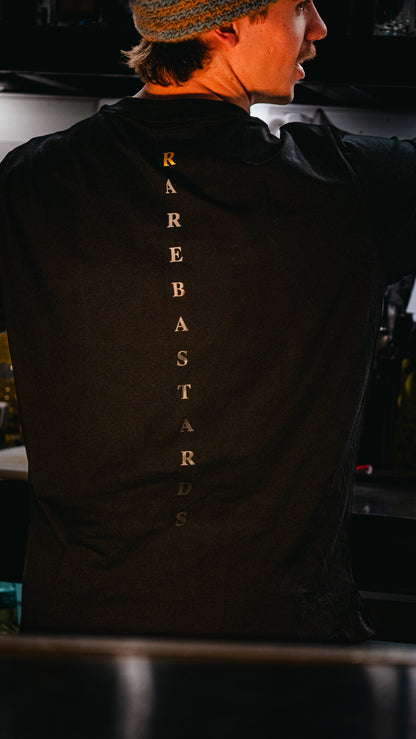 A man wearing a black t-shirt with gold details with fading text